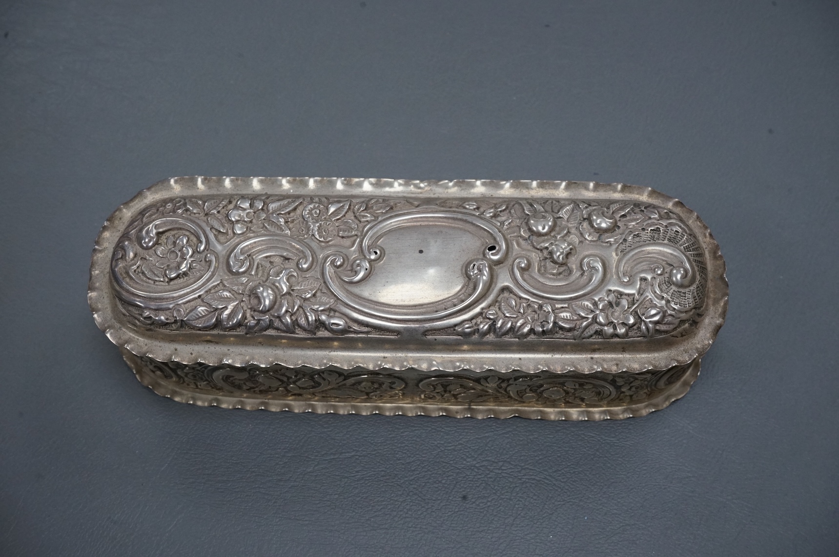 An early 20th century repousse silver dressing table tray by William Comyns & Sons Ltd, London, 1901, 25.1cm, together with a matching oval trinket box, London, 1900, 16.6oz (a.f.).